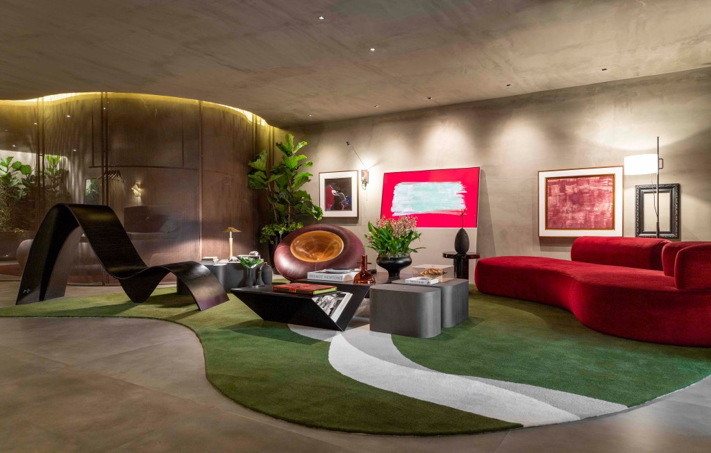 Léo Shehtman - Memórias. Projeto da CASACOR São Paulo 2023. Na foto, sala com sofá vermelho, estante, poltronas e tapete