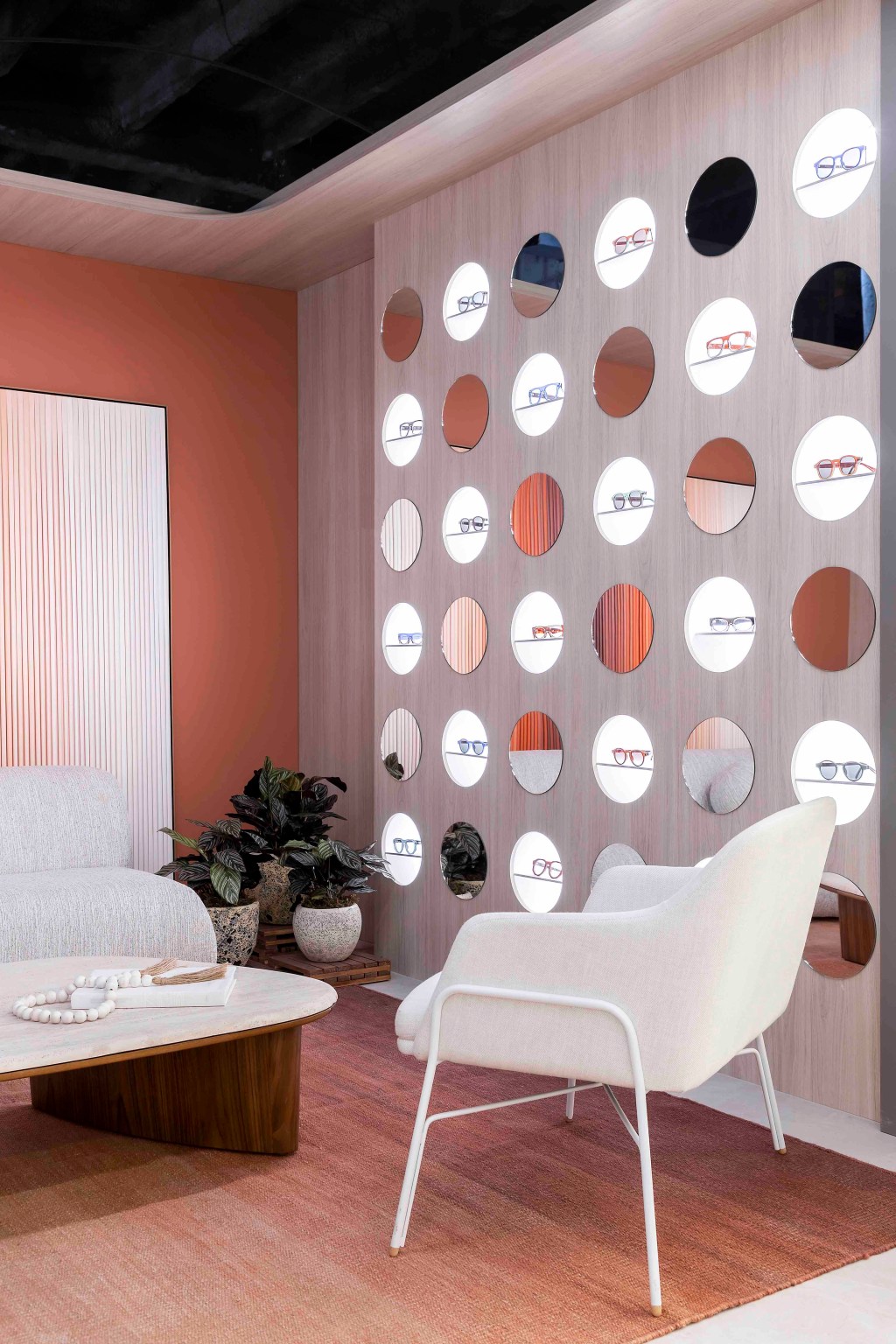 Letícia Nannetti - Olhar Essencial. Projeto da CASACOR São Paulo 2023. Na foto, sala com parede em degradê e sofá curvo. Expositor de óculos com nichos redondos.
