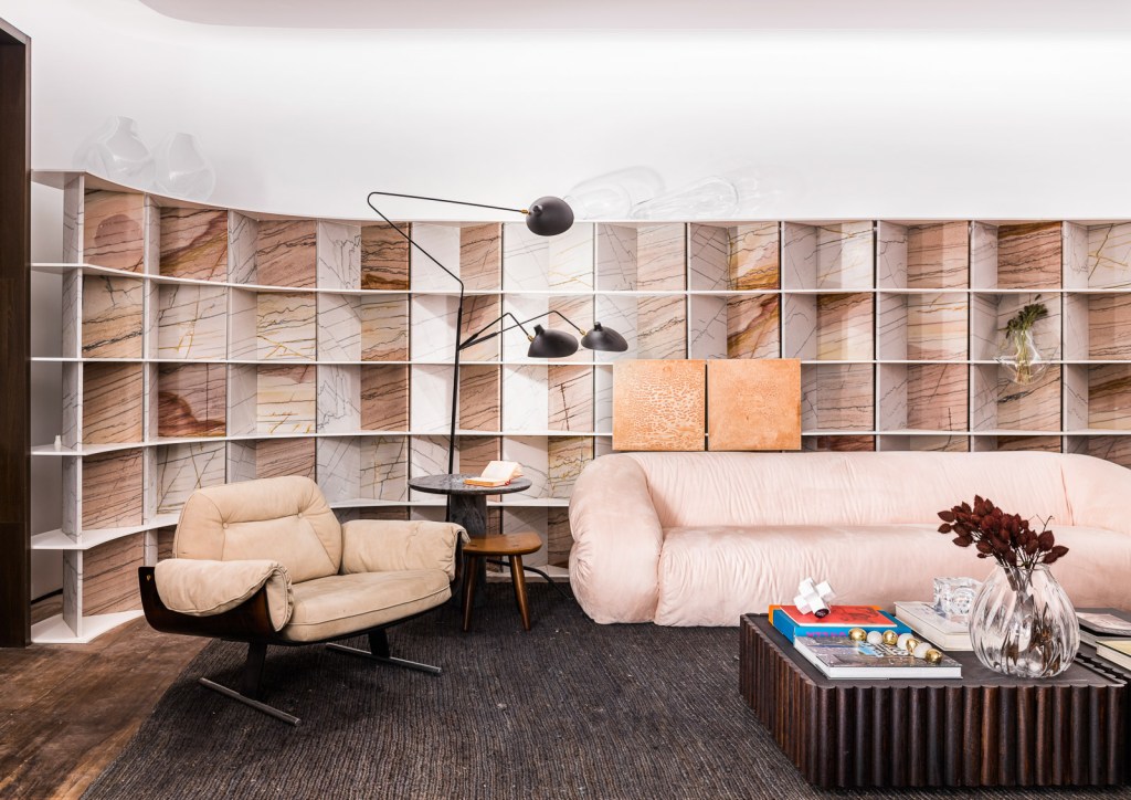 Marcela Penteado Arquitetos - Loft 011. Projeto da CASACOR São Paulo 2023. Na foto, sala de estar com estante curva, tapete e sofa.