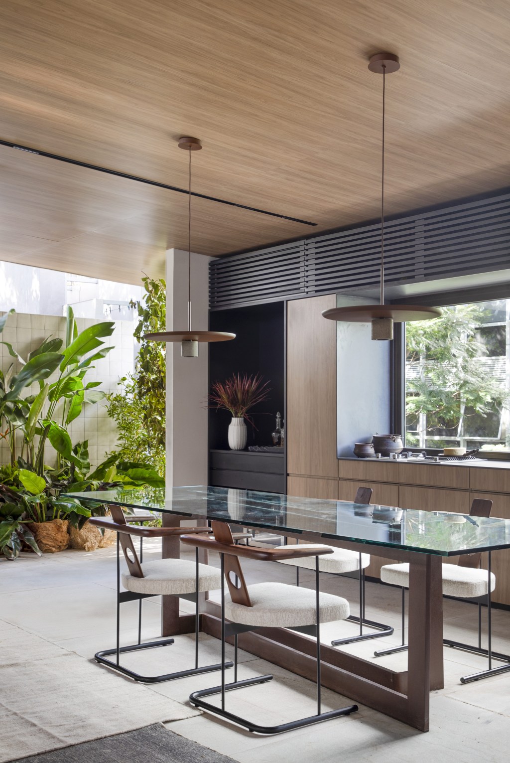 Navarro Arquitetura - Casa Araxá. Projeto da CASACOR São Paulo 2023. Na foto sala de jantar com mesa de vidro e cozinha.