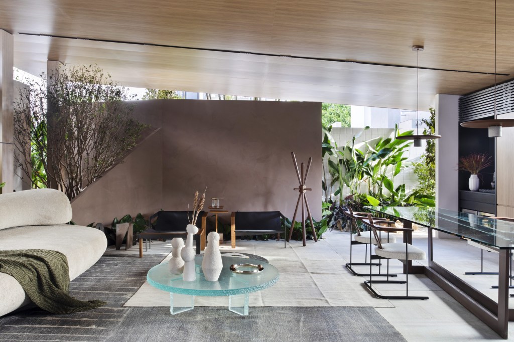 Navarro Arquitetura - Casa Araxá. Projeto da CASACOR São Paulo 2023. Na foto, sala de estar e jantar com sofá curvo, tapete e mesa.
