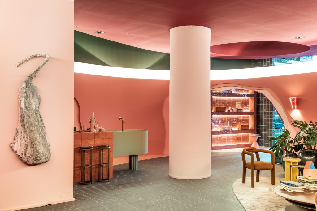 Ricardo Abreu - Casa Coral. Projeto da CASACOR São Paulo 2023. Sala com paredes rosas, cozinha com bancada verde e iluminação cenica.