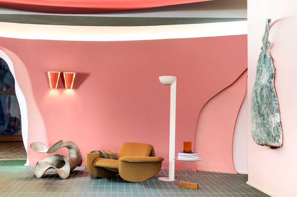 Ricardo Abreu - Casa Coral. Projeto da CASACOR São Paulo 2023. Na foto, sala com parede rosa, poltrona marrom e luminárias.