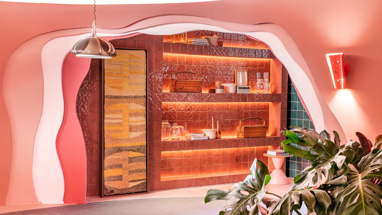 Ricardo Abreu - Casa Coral. Projeto da CASACOR São Paulo 2023. NA foto, estante de cerâmica rosa, tapeçaria e parede com recorte orgânico.