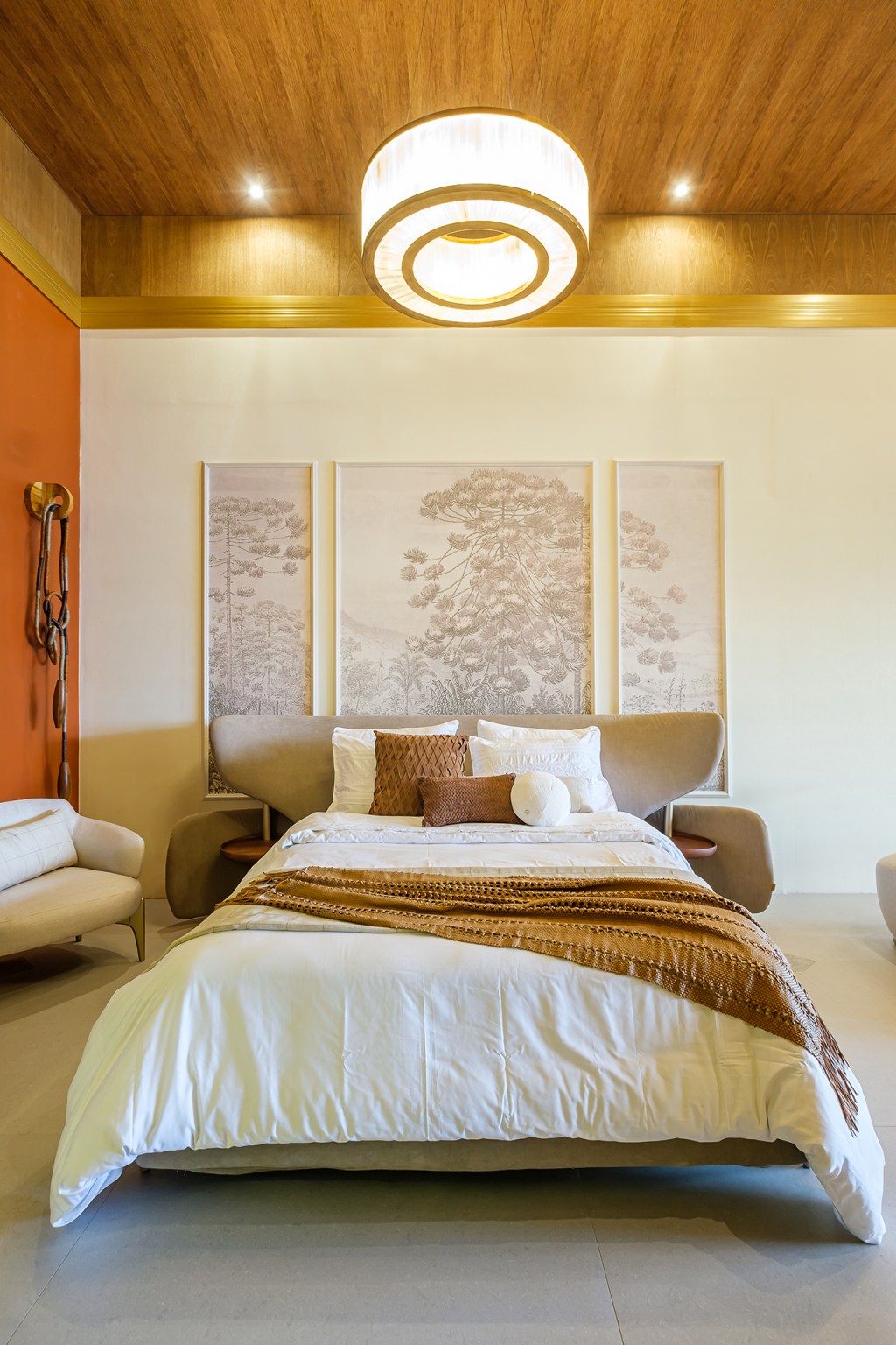 Taynara Wazilewski - Loft Terra Rossa. Projeto da CASACOR Bolívia 2023. Na foto, quarto com quadros na cabeceira, teto de madeira e parede laranja.