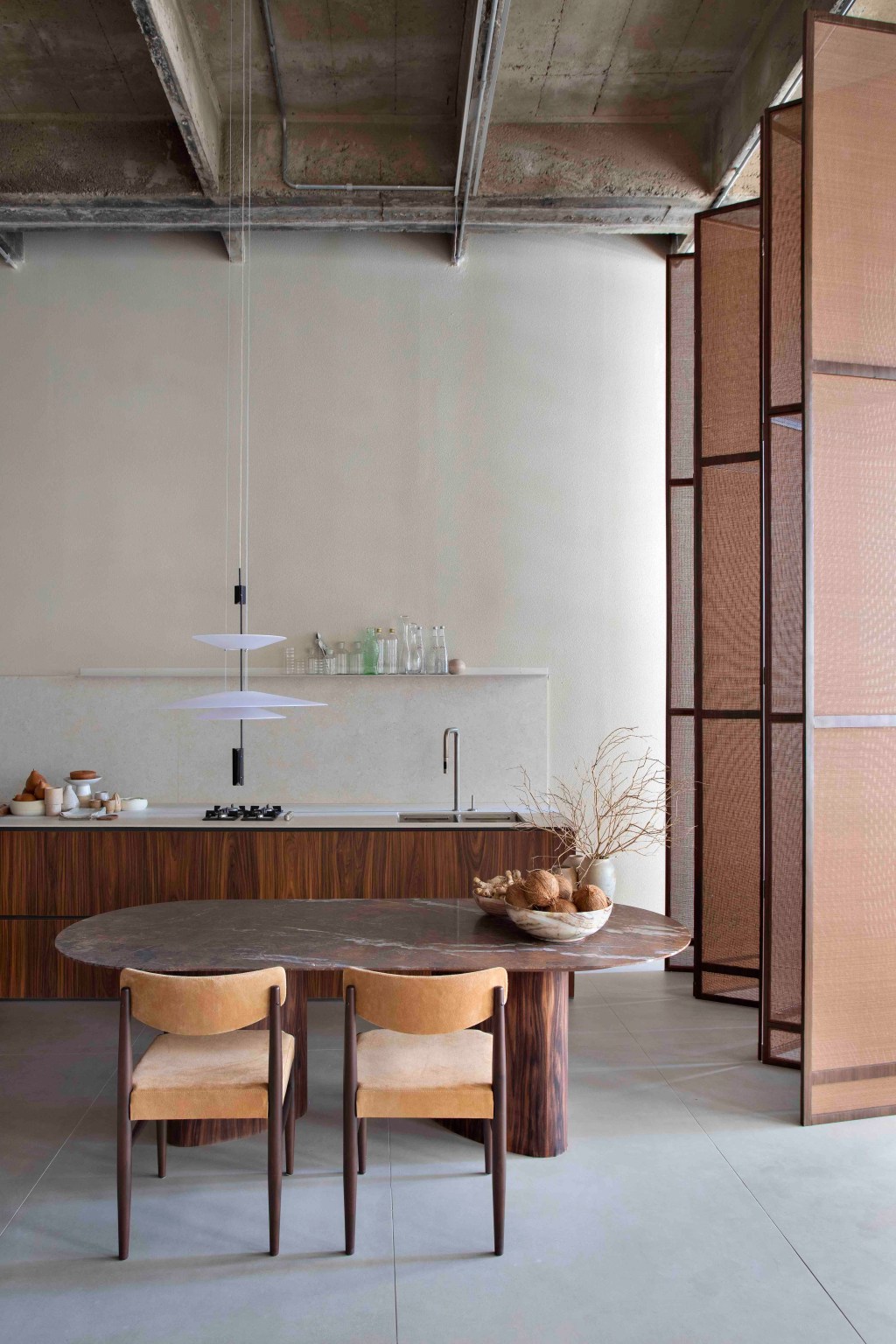 Ticiane Lima - Loft (In)terno. Projeto da CASACOR São Paulo 2023. Na foto, sala de jantar e cozinha com porta vazada, luminária e cadeira.