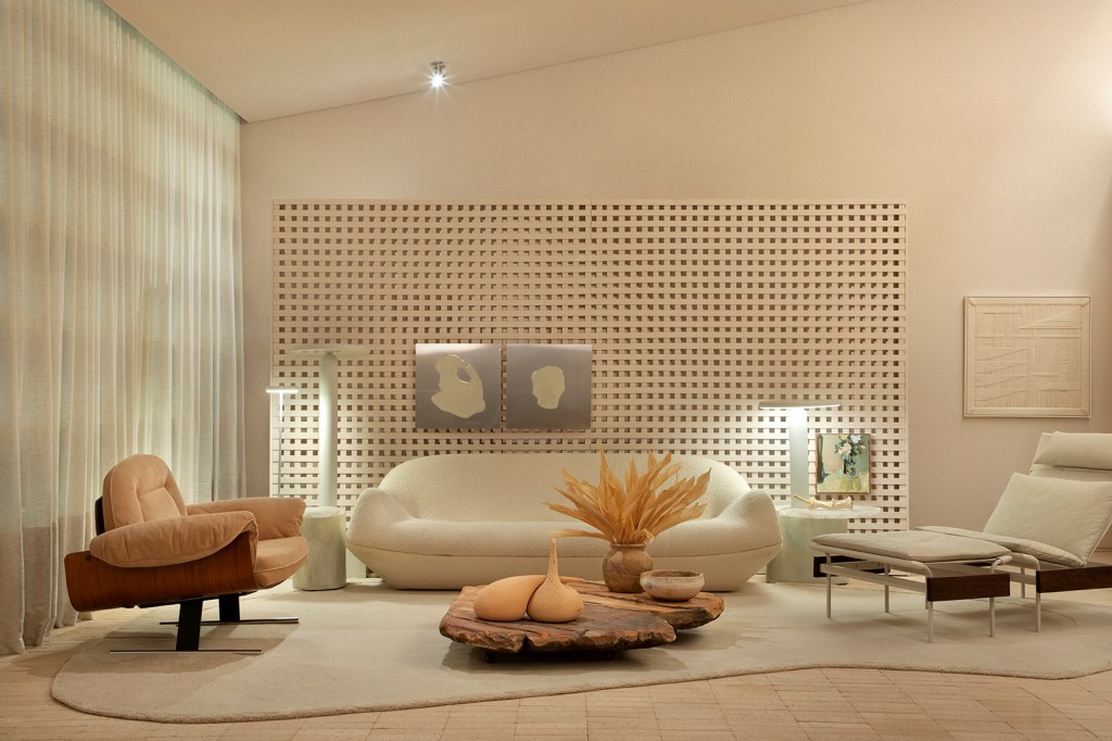 Très Arquitetura - Loft Celmar. Projeto da CASACOR São Paulo 2023. Na foto, sala com parede vazada, tijolo no piso, e sofás em tons terrosos.