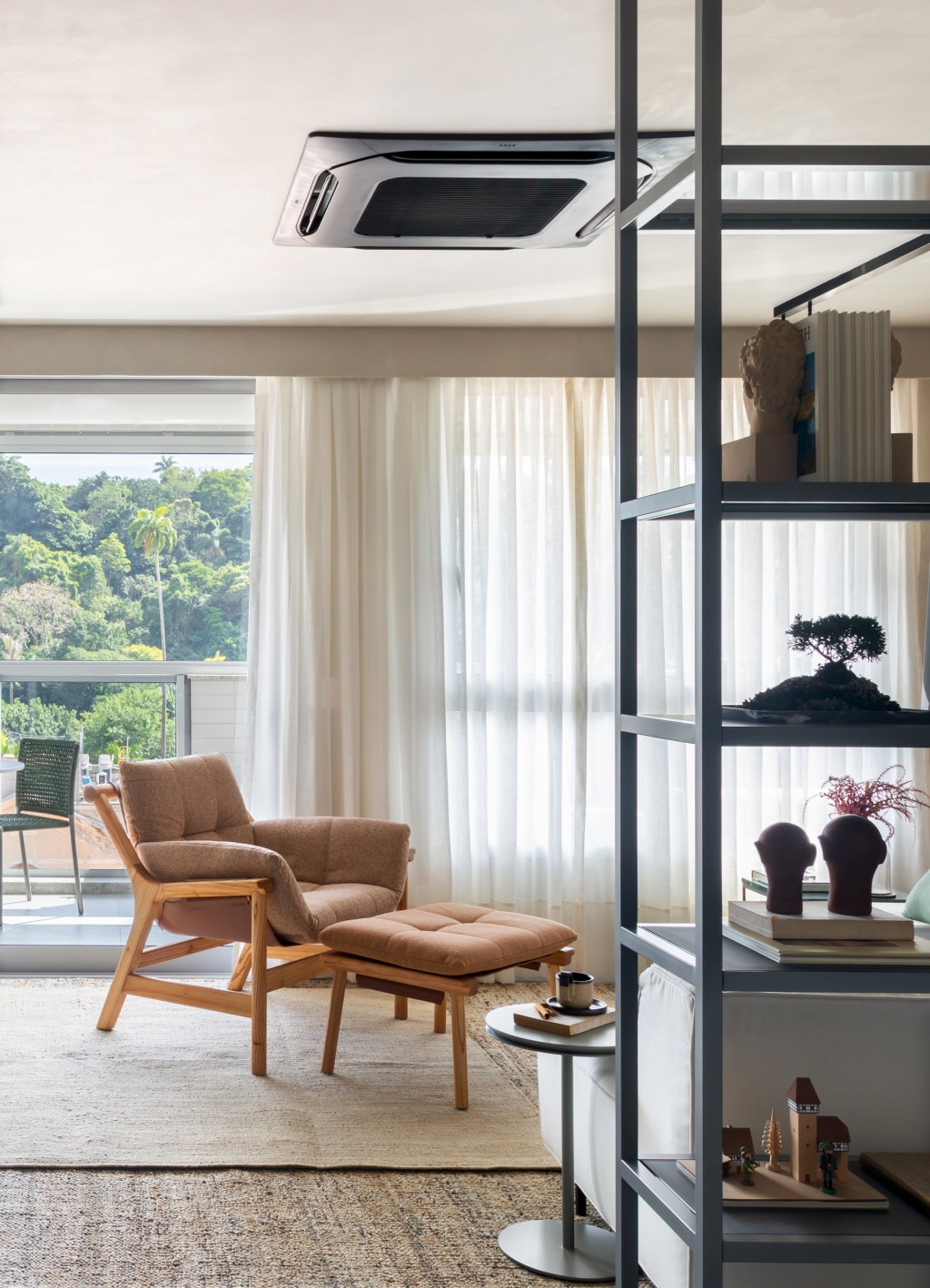 Apê de 82 m² ganha décor japandi com toques contemporâneos. Projeto de Fabiano Ravaglia. Na foto, sala de estar com estante de serralheria, poltrona e varanda.