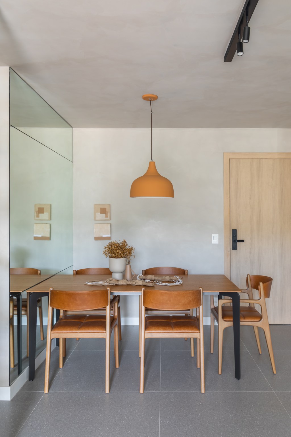 Apê de 82 m² ganha décor japandi com toques contemporâneos. Projeto de Fabiano Ravaglia. Na foto, sala de jantar com parede com espelho e cadeiras de couro.