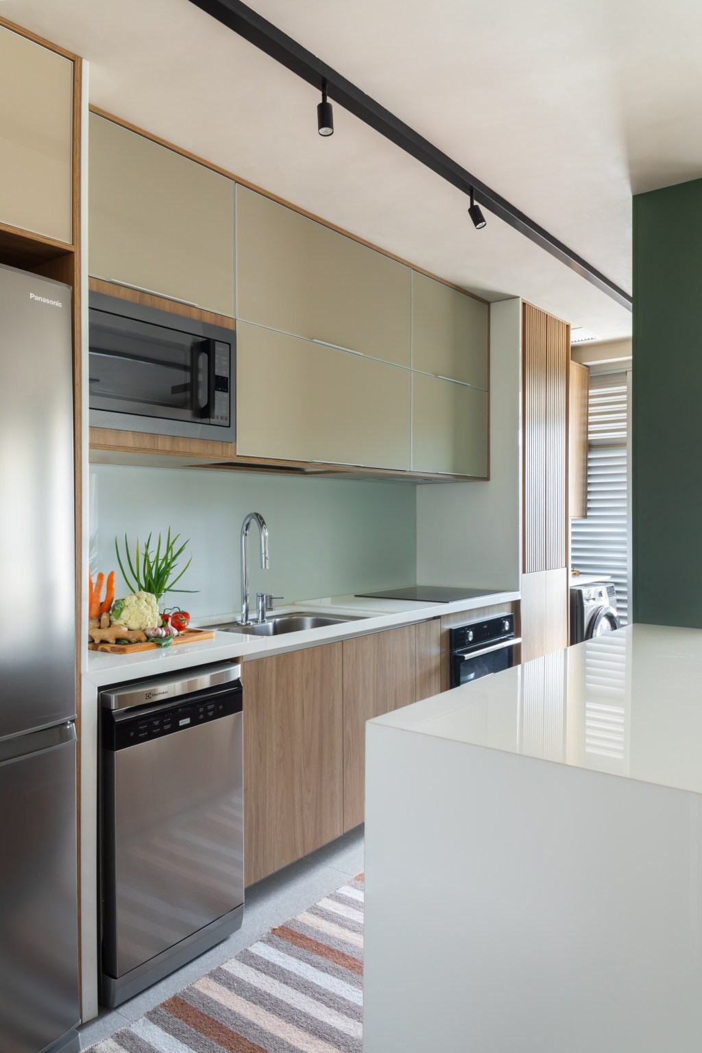 Apê de 82 m² ganha décor japandi com toques contemporâneos. Projeto de Fabiano Ravaglia. Na foto, cozinha americana com parede verde e balcão branco.