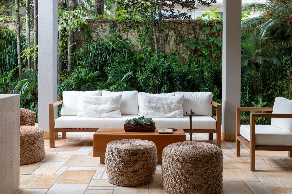 Cacau Ribeiro assina casa charmosa perfeita para a vida em família. Na foto, varanda com poltronas e jardim.