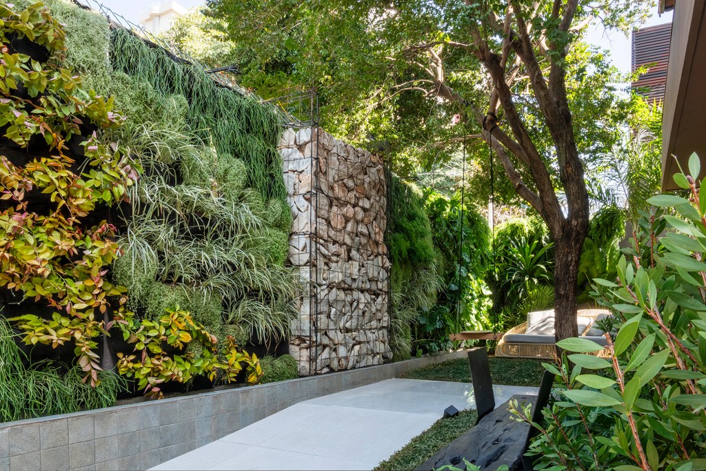 Victor Thauan - Refúgio do Mato. Projeto da CASACOR Minas Gerais 2023. Na foto, jardim com parede verde, banco e muro de pedras.