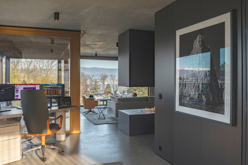 David Bastos projeta apartamento na Suíça repleto de design assinado. Na foto, sala com lareira, home office e paredes pretas,