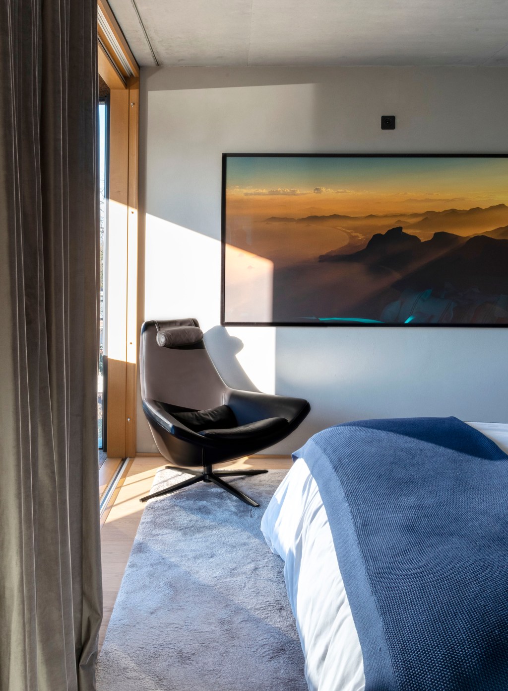 David Bastos projeta apartamento na Suíça repleto de design assinado. Na foto, quarto com varanda e poltrona.