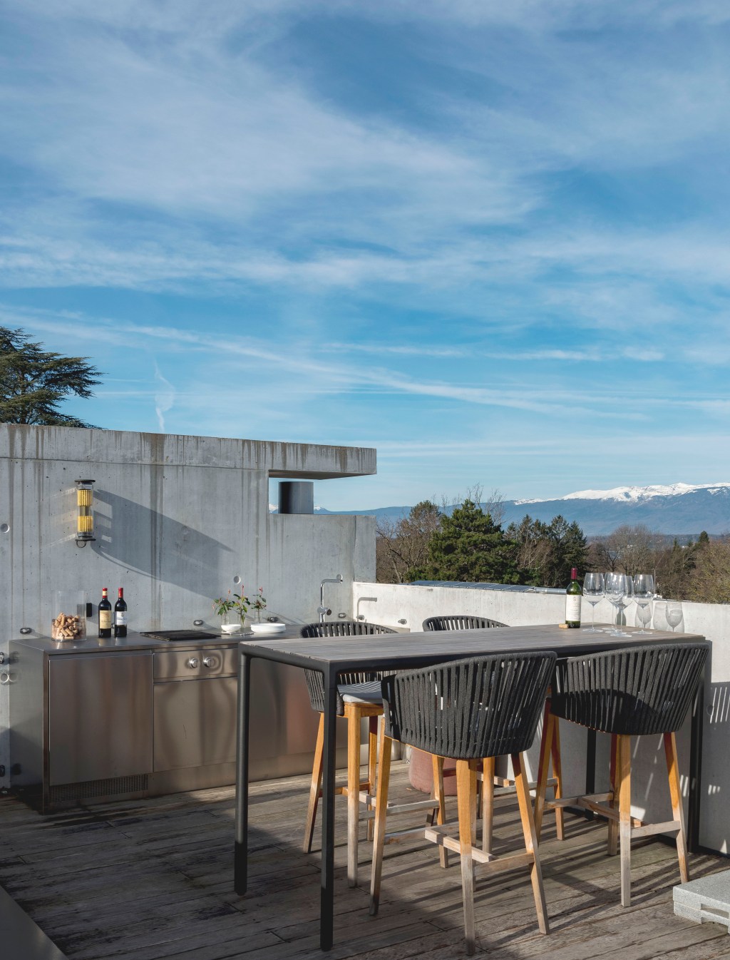 David Bastos projeta apartamento na Suíça repleto de design assinado. Na foto, varanda gourmet com mesa, bancada e vista para as montanhas.