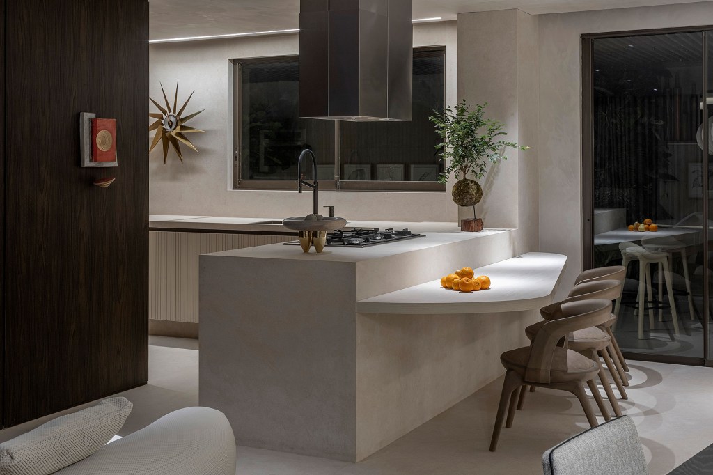 Gislene Lopes - Apartamento Casa Ferolla. Projeto da CASACOR Minas Gerais 2023. Na foto, cozinha americana com bancada, parede de madeira e mesa triangular.