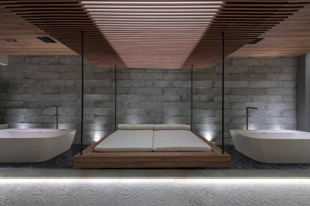 Janaina Araújo - Imersão Deca. Projeto da CASACOR Minas Gerais 2023. Na foto, banheiro com cama suspensa, banheira, pergolado, madeira e pedra.