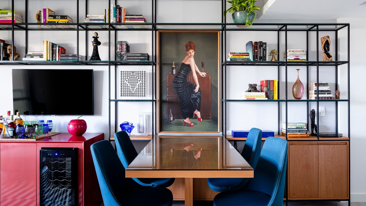 Loft de 45 m² ganha décor descolado baseado na coleção de arte do morador. Projeto de Vivian Reimers. Na foto, sala com quadro, estante de serralheria e tapete listrado.