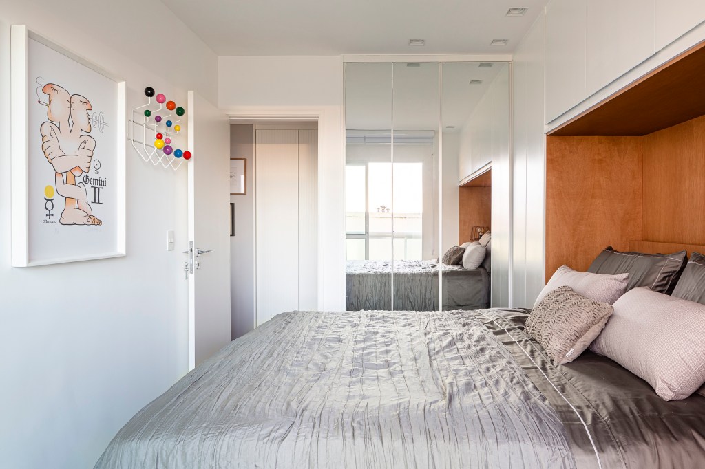 Loft de 45 m² ganha décor descolado baseado na coleção de arte do morador. Projeto de Vivian Reimers. Na foto, quarto com cama embutida na marcenaria, armario com espelho e quadros.