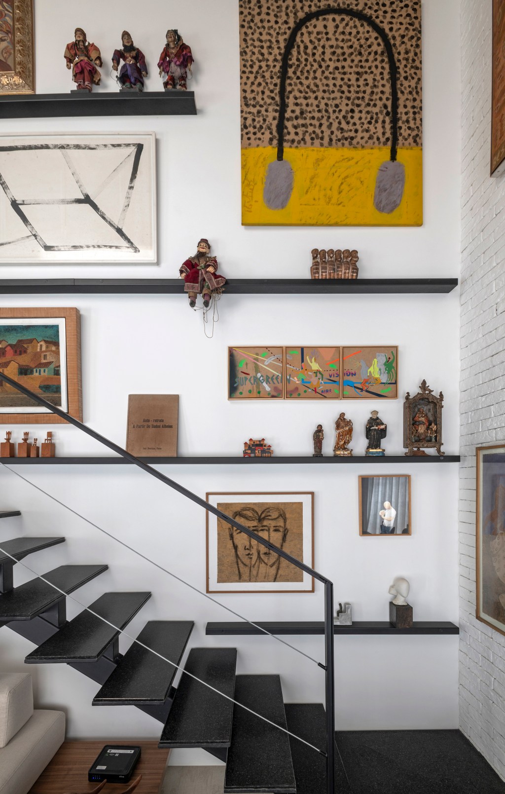 Loft de 64 m² ganha décor industrial e coleção de arte dos moradores. Projeto de Junior Piacesi. Na foto, escada com gallery wall na parede.
