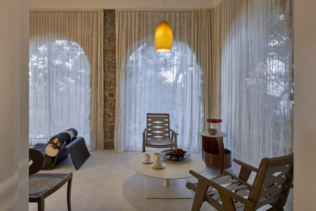 Pedro Lázaro Arquitetura - Sala da Lareira e Varanda. Projeto da CASACOR Minas Gerais 2023. Na foto, varanda com cadeira, poltrona e cortinas.