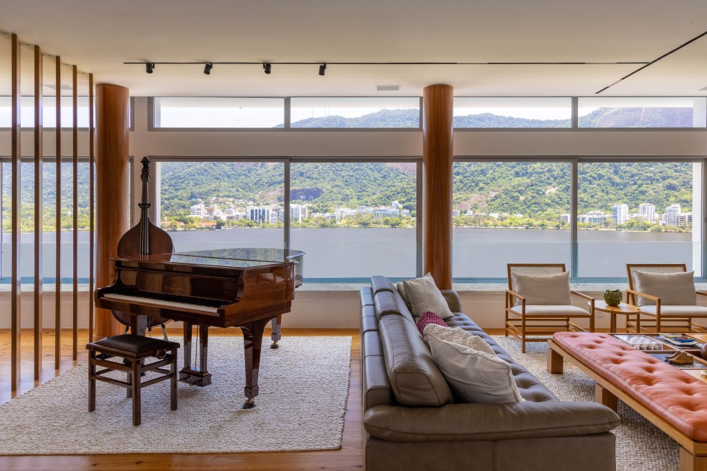 Triplex tem estúdio de música, entrada privativa da rua e vista para Lagoa, Projeto Maurício Nóbrega. Na foto, sala de estar com piano, sofás e vista para a Lagoa.