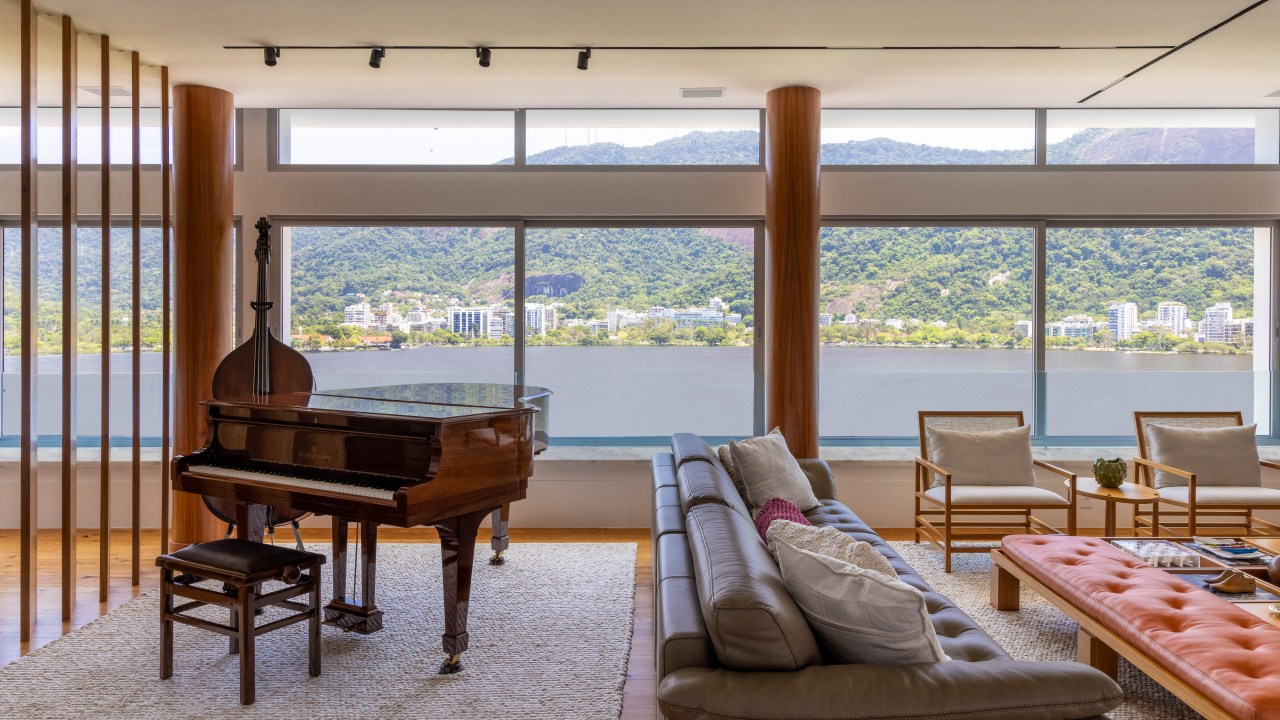 Triplex tem estúdio de música, entrada privativa da rua e vista para Lagoa, Projeto Maurício Nóbrega. Na foto, sala de estar com piano, sofás e vista para a Lagoa.