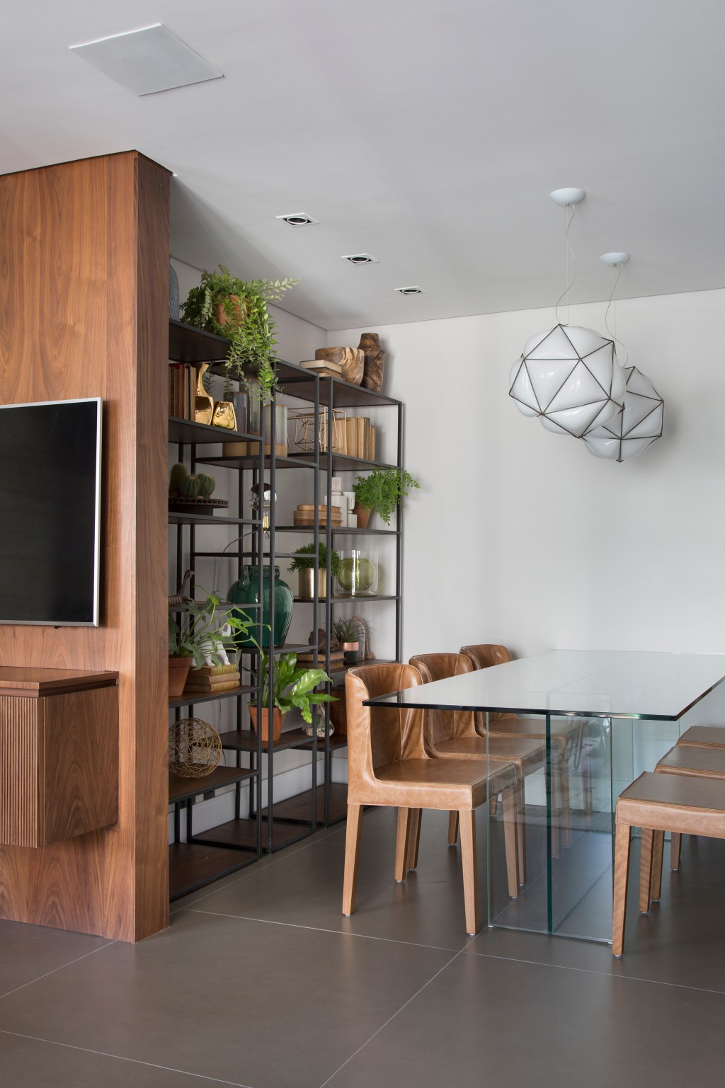 Apê de 95 m² ganha décor masculino para receber amigos e clientes. Projeto de Fabiano Ravaglio. Na foto, sala de jantar com estante de serralheria e plantas.
