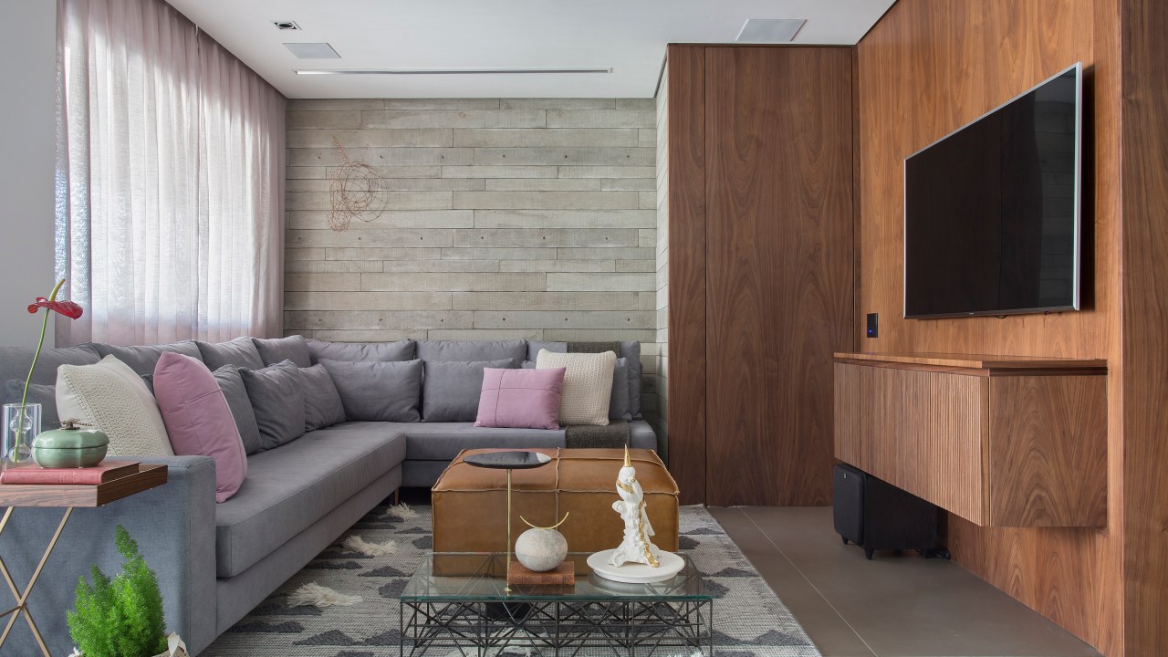 Apê de 95 m² ganha décor masculino para receber amigos e clientes. Projeto de Fabiano Ravaglio. Na foto sala com varanda e sofá em L. Porta camuflada na marcenaria.