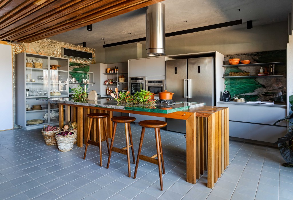Cozinha Ágape, projeto de Tatiana Melo para a CASACOR Bahia 2023. Na foto, cozinha com ilha, horta de temperos e marcenaria cinza.