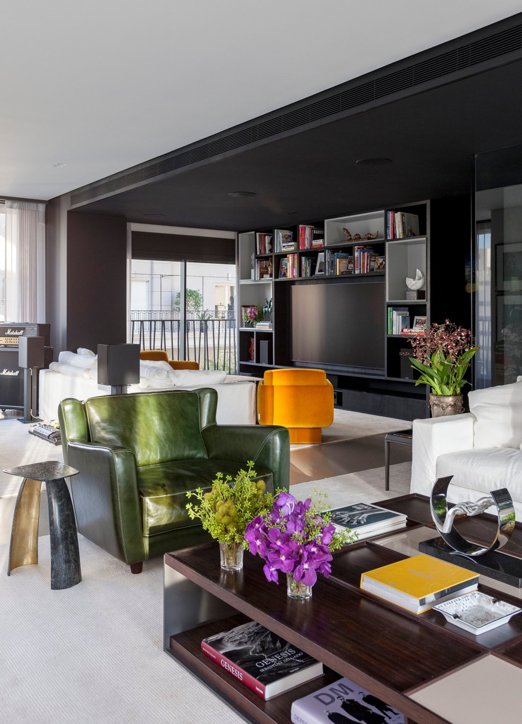 David Bastos assina apê de 268 m² com décor sóbrio e elegante. Na foto, sala de estar com estante preta e poltrona.