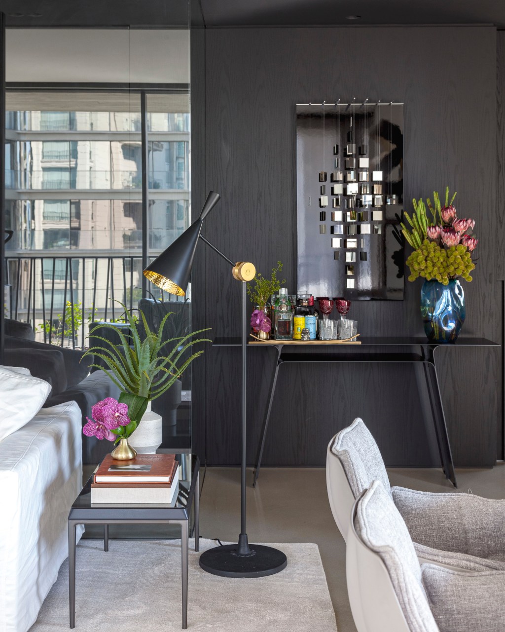 David Bastos assina apê de 268 m² com décor sóbrio e elegante. Na foto, sala de estar com parede preta, luminária de piso e bar.