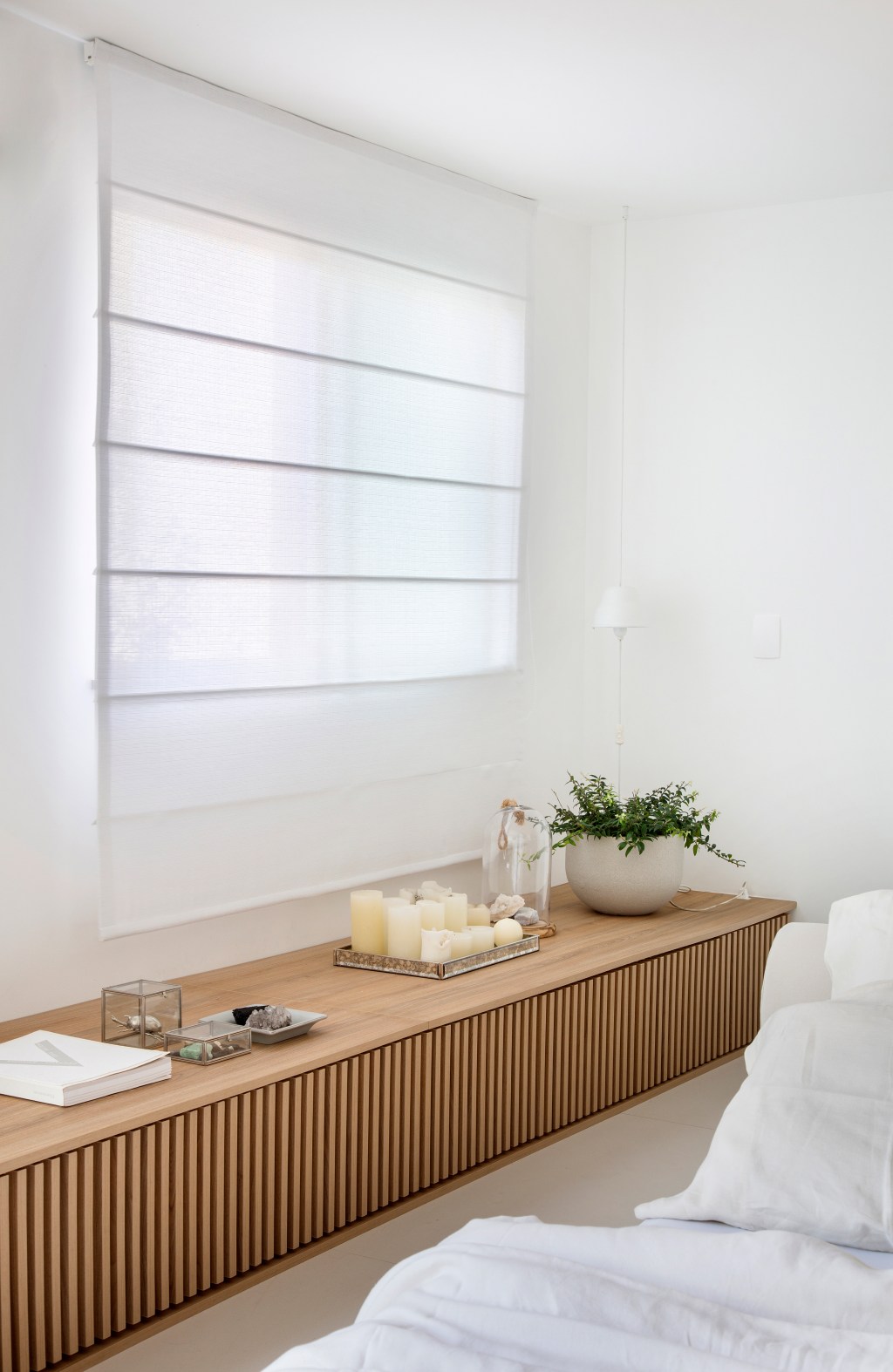 Loft de 40 m² ganha projeto minimalista que une branco e madeira. Projeto de Diego Raposo e Manuela Simas. Na foto, banco de marcenaria ripada no quarto.
