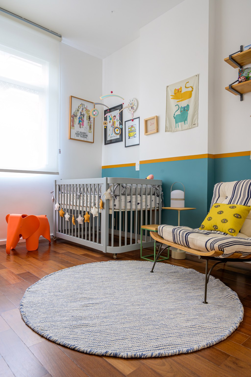 Pilar estrutural e tijolos aparentes dão o tom deste apê de 115 m². Projeto de Ana Neri. Na foto, quarto de bebê com berço, quadros e meia-parede.