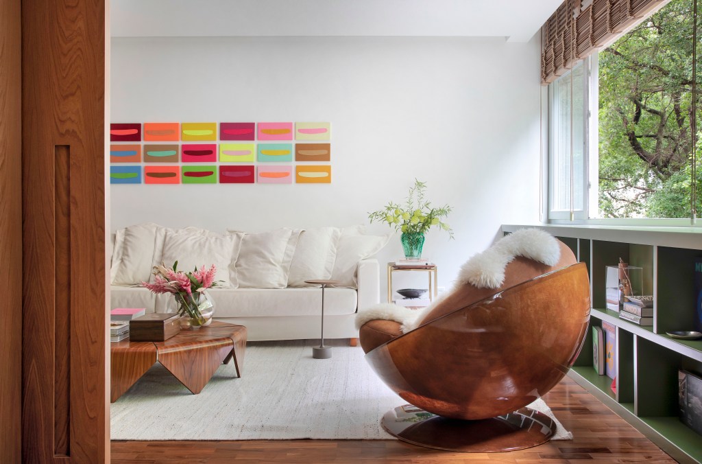 Apartamento em Ipanema é repleto de mobiliário de design brasileiro. Projeto de Bianca Da Hora. Na foto, sala de estar com aparador verde e quadros.