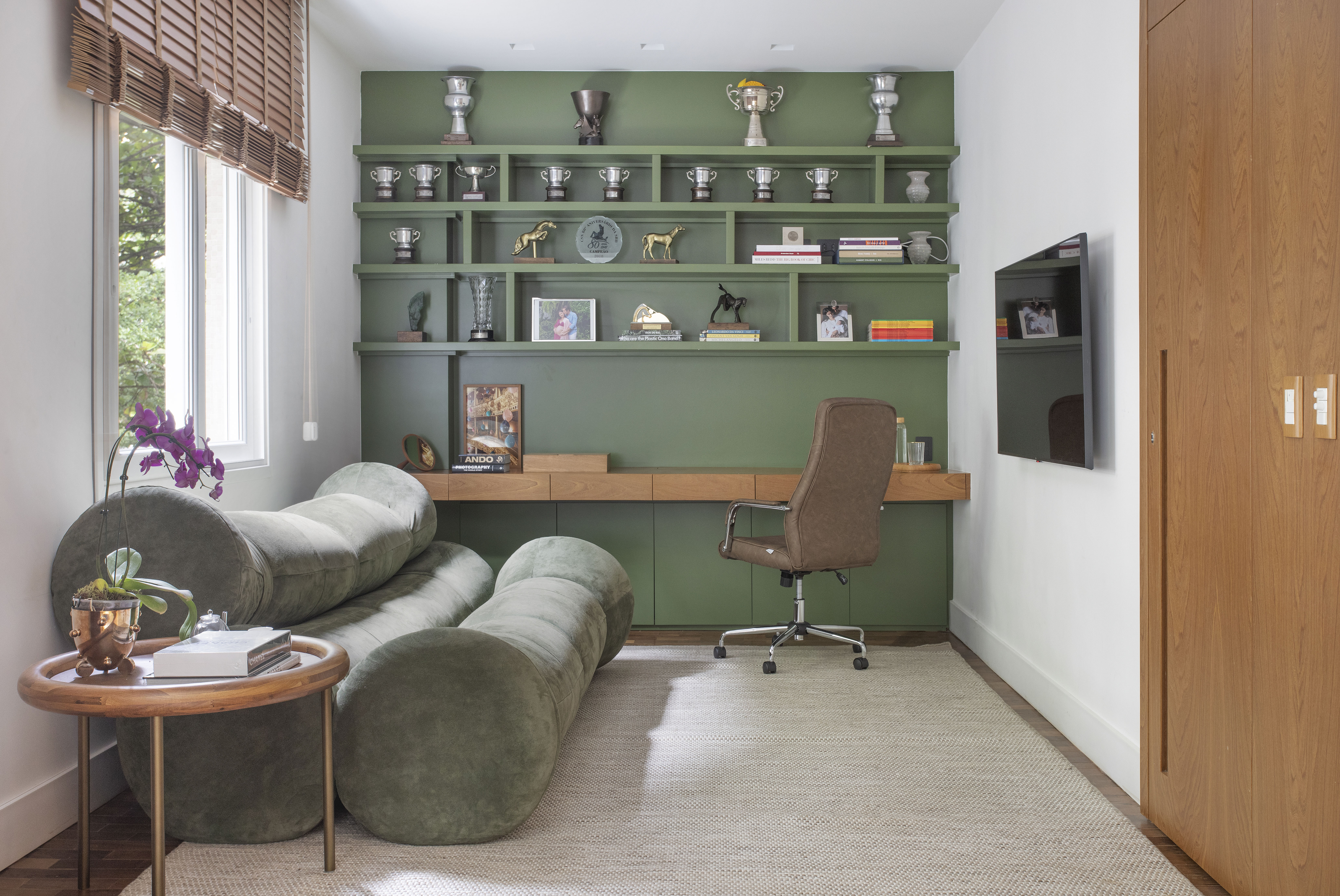Apartamento em Ipanema é repleto de mobiliário de design brasileiro. Projeto de Bianca Da Hora. Nas foto, home office, com marcenaria verde e sofá verde,