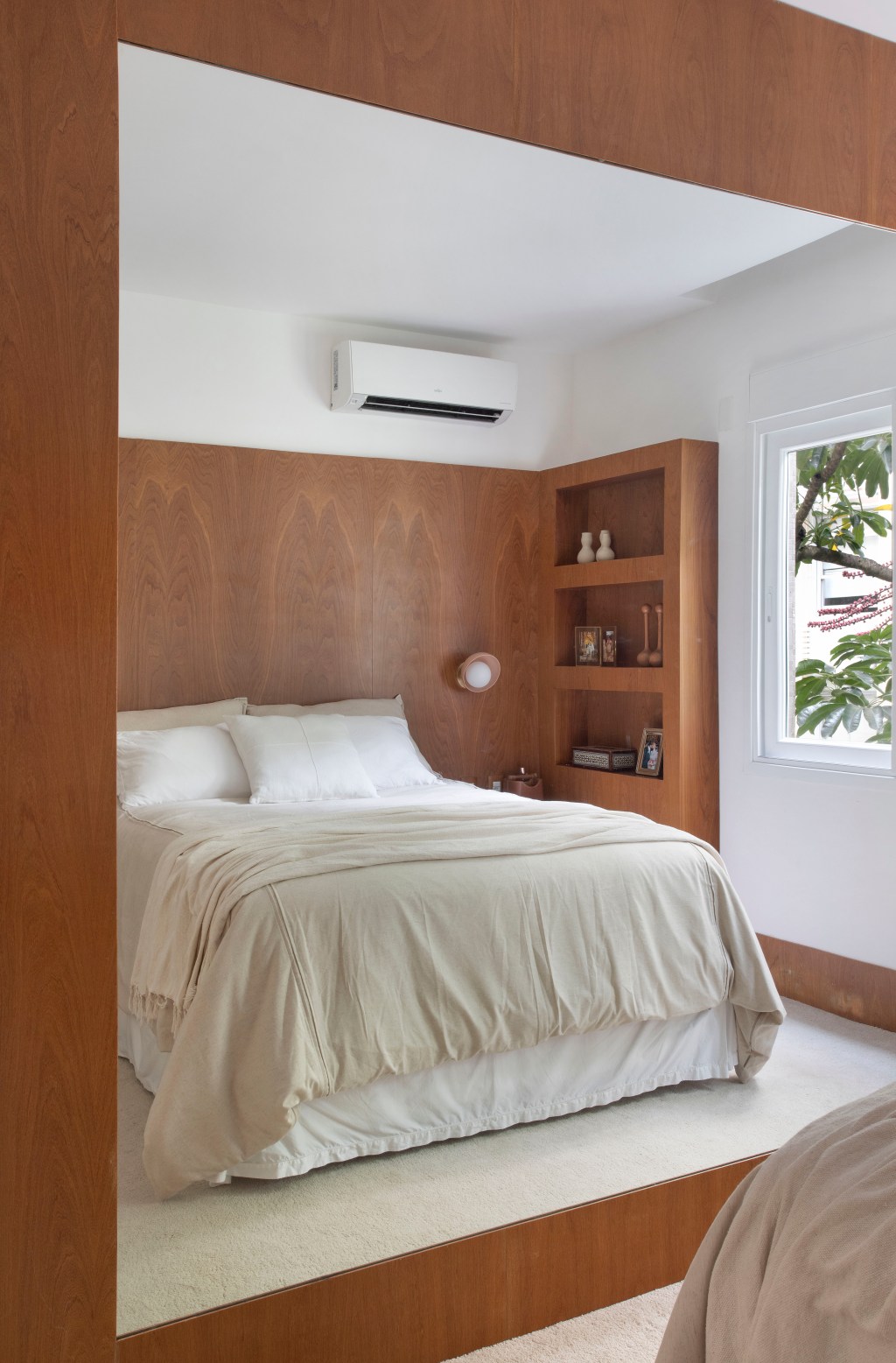 Apartamento em Ipanema é repleto de mobiliário de design brasileiro. Projeto de Bianca Da Hora. Na foto, quarto de casal com painel de madeira e tapete.
