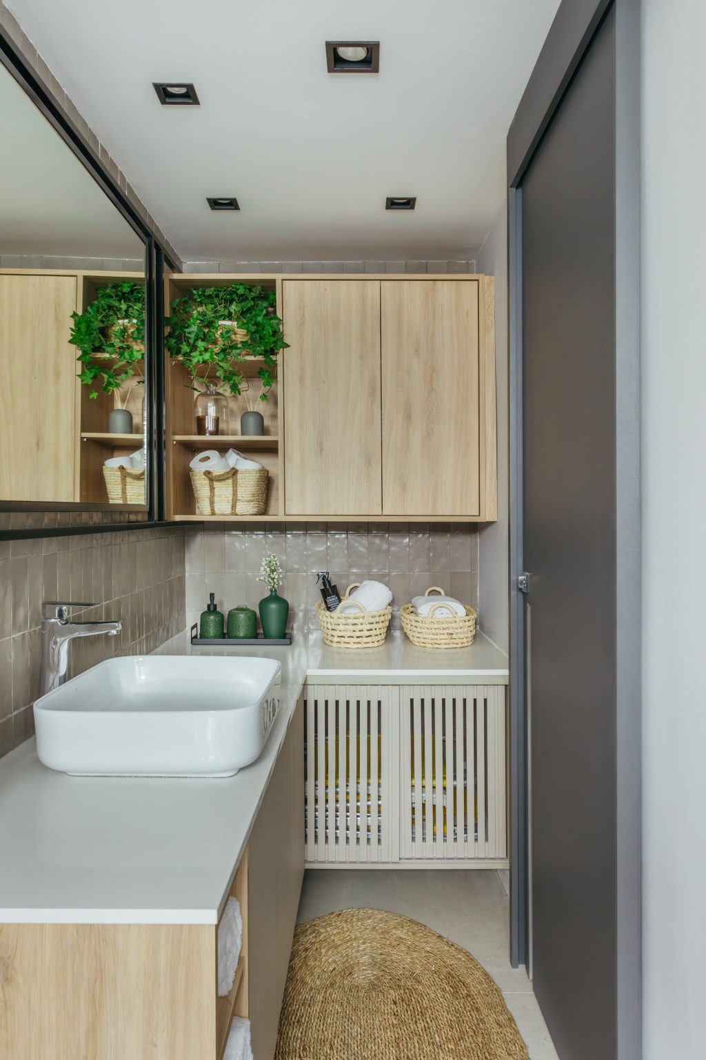Cozinha se esconde dentro do armário neste apê de 35 m², Projeto de Ikeda Arquitetura. Na foto, banheiro com marcenaria clara e espelho de serralheria.