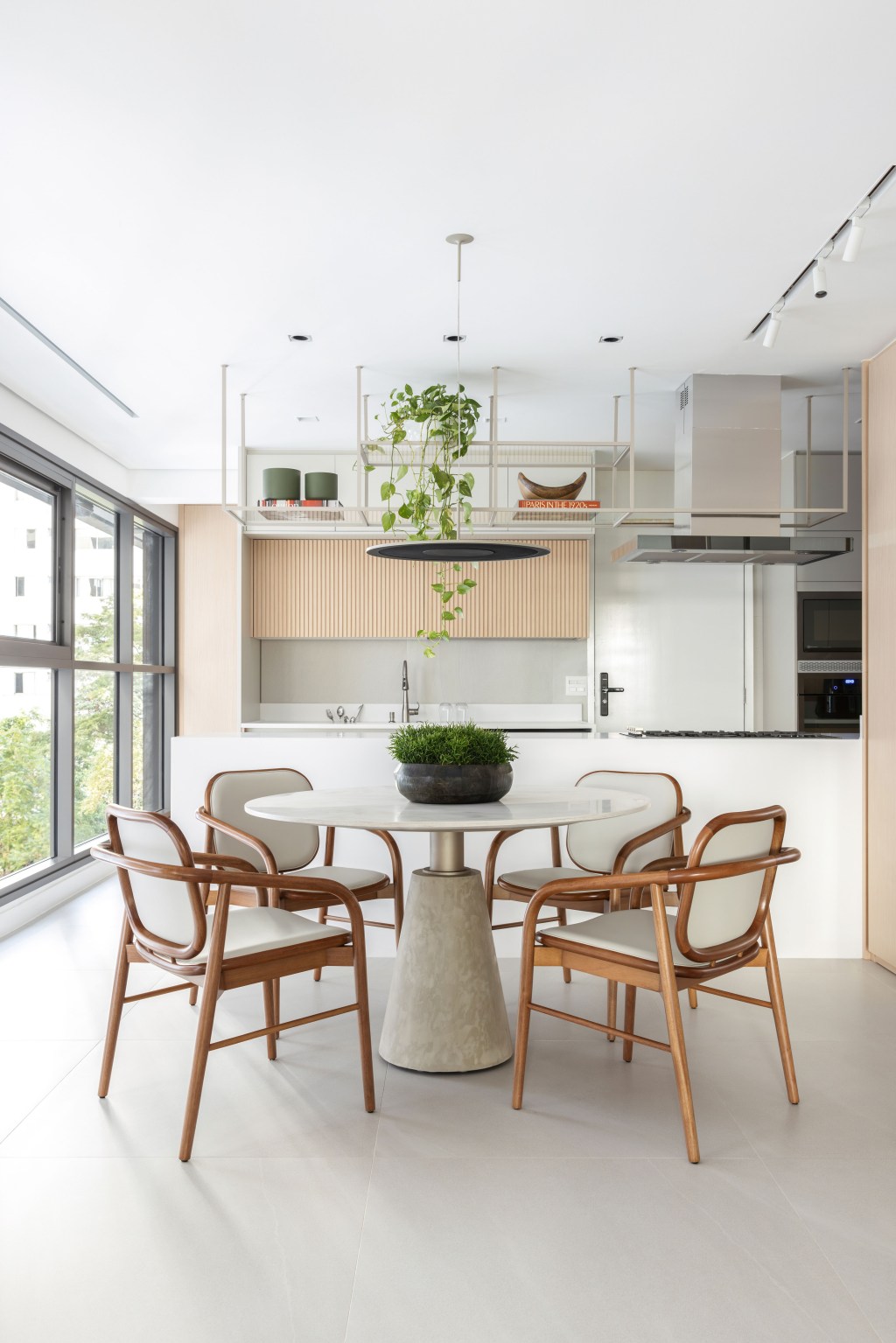 Décor neutro e ambientes integrados e fluidos marcam apartamento de 140 m². Projeto de Paula Muller. Na foto, varanda gourmet com bancada, mesa redonda e marcenaria ripada.