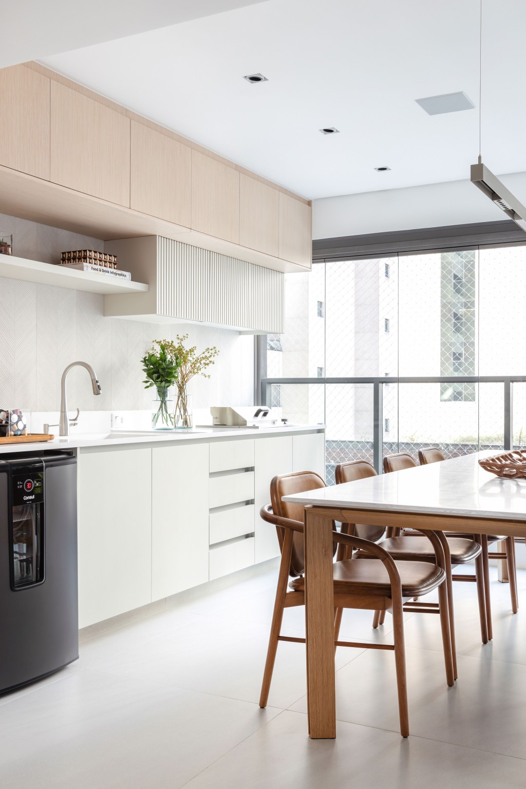 Décor neutro e ambientes integrados e fluidos marcam apartamento de 140 m². Projeto de Paula Muller. Na foto, varanda gourmet com mesa de jantar e frigobar.