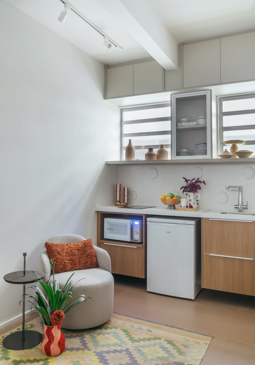 Loft de 30 m² é projetado para administradora de 80 anos que mora sozinha. Projeto de Richard de Mattos, da Casa Cururu. Na foto, cozinha com armários de madeira e tampo branco.