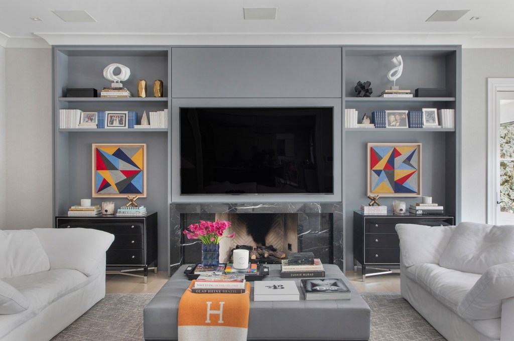 Marcelo Salum moderniza casa de 1300 m² em Chicago. Na foto, sala de TV com quadros, marcenaria cinza e sofás.