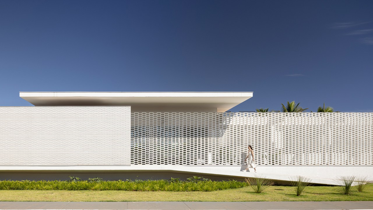 Tijolos brancos e vazados compõem fachada de casa de 600 m² em Brasília. Projeto de Bloco Arquitetos. Na foto, fachada da casa com muro de tijolos vazados.