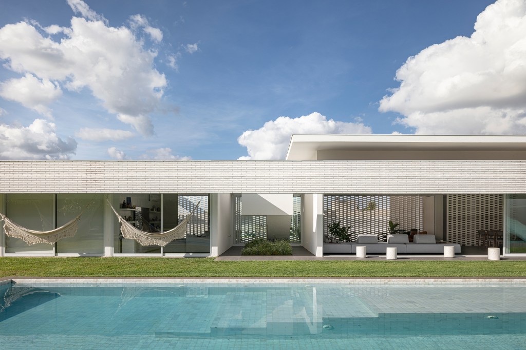 Tijolos brancos e vazados compõem fachada de casa de 600 m² em Brasília. Projeto de Bloco Arquitetos. Na foto, quartos voltados para o jardim.