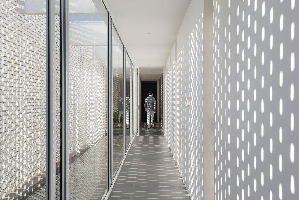 Tijolos brancos e vazados compõem fachada de casa de 600 m² em Brasília. Projeto de Bloco Arquitetos. Na foto, corredor com muros de tijolo vazado.