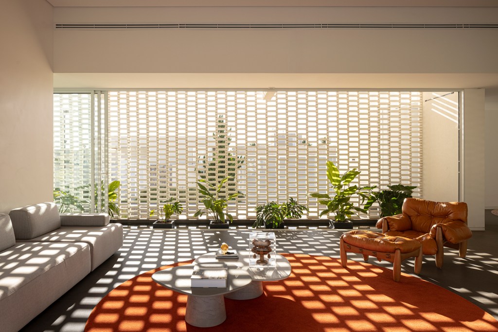 Tijolos brancos e vazados compõem fachada de casa de 600 m² em Brasília. Projeto de Bloco Arquitetos. Na foto, sala com parede tijolo vazado.