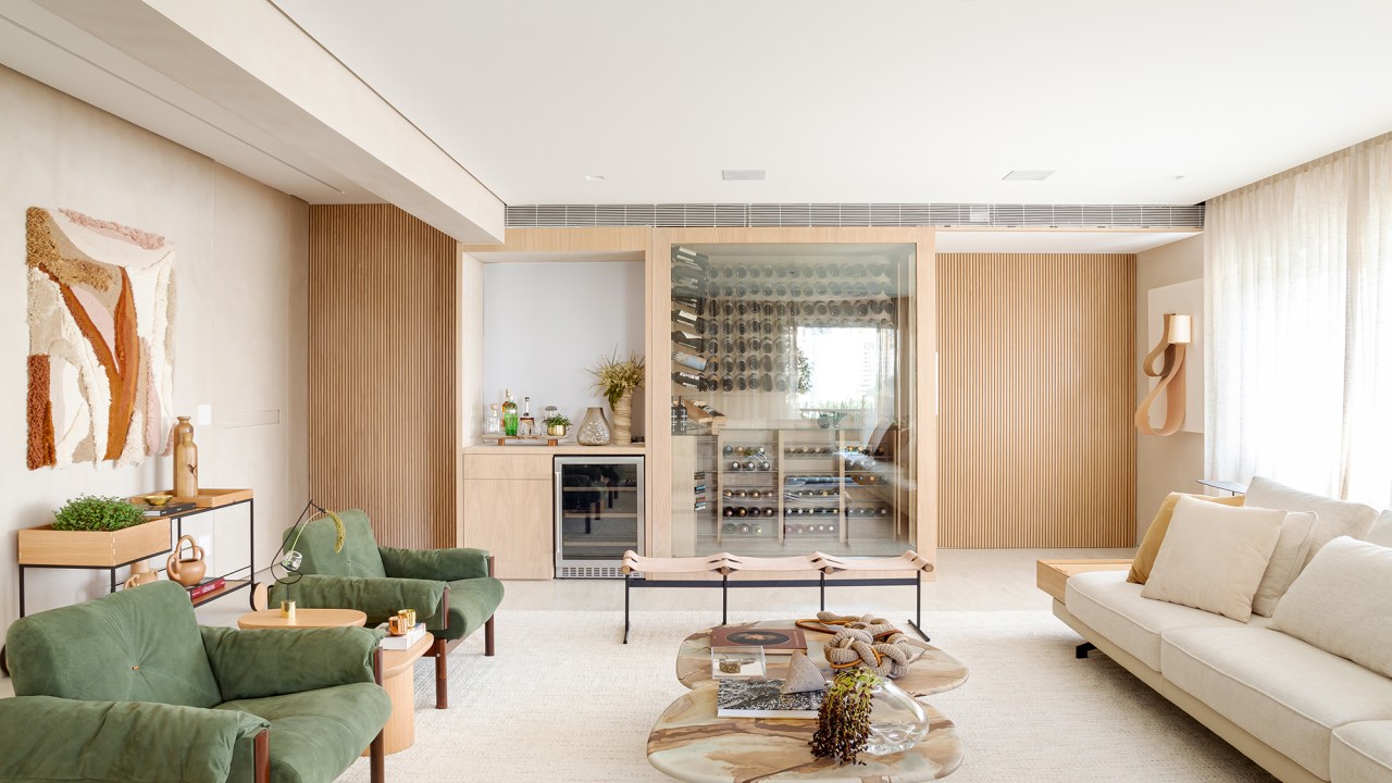 Adega walk-in e muita madeira marcam este apartamento de 300 m². Projeto de Figueiredo Fischer Arquitetos. Na foto, sala de de estar e jantar, com sofá, mesa, poltronas verdes e mesa de centro.