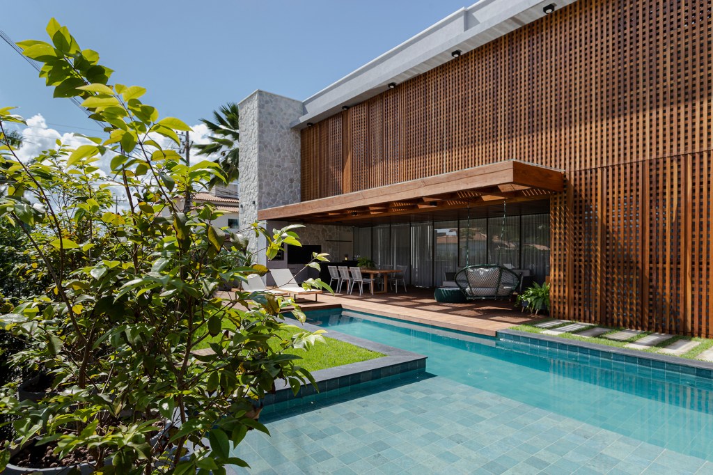 Fachada de muxarabis filtra o sol nesta casa de 430 m² na Bahia. Projeto de Sidney Quintela. Na foto, fachada da casa com muxarabi, varanda e piscina.