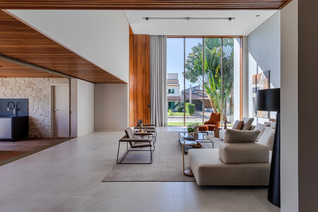 Fachada de muxarabis filtra o sol nesta casa de 430 m² na Bahia. Projeto de Sidney Quintela. Na foto, sala de estar com pé-direito duplo e vista para o jardim.
