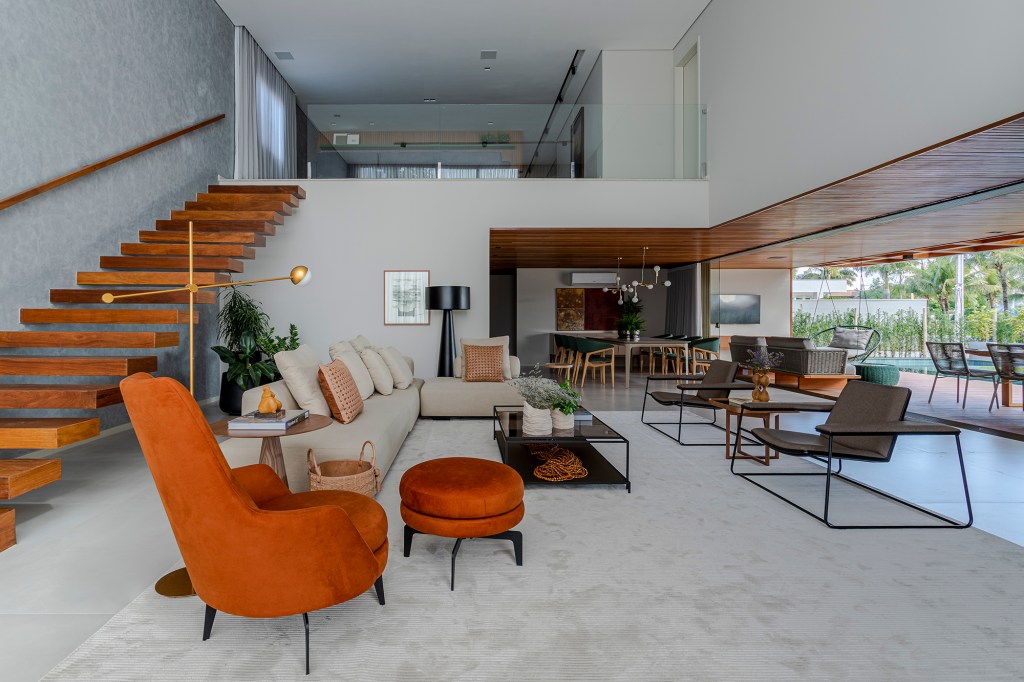 Fachada de muxarabis filtra o sol nesta casa de 430 m² na Bahia. Projeto de Sidney Quintela. Na foto, sala com escada, sofá, poltrona. Sala de estar e varanda integrada.